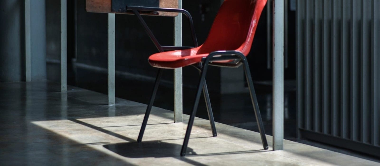 An adjustable perch stool beside a height-adjustable desk